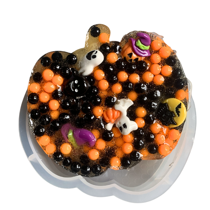 Close up of pumpkin shaped picky pad filled with black and orange beads and halloween ghost charms.